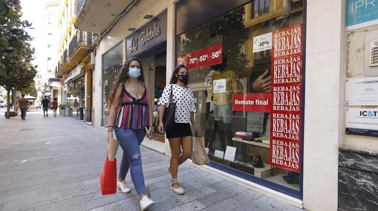 Dos jóvenes pasan delante de una tienda del Centro, durante las rebajas de verano de 2020