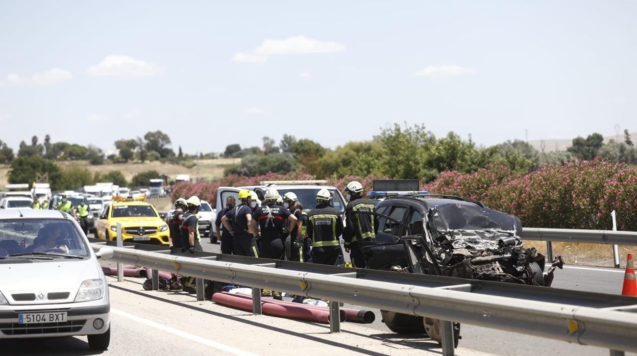 Los bomberos trabajan en la autovía A-4 con el vehículo siniestrado esta mañana