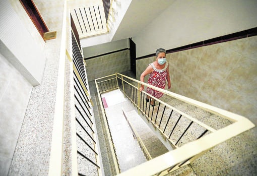 Una mujer sube por las escaleras de su bloque sin ascensor en la Fuensanta