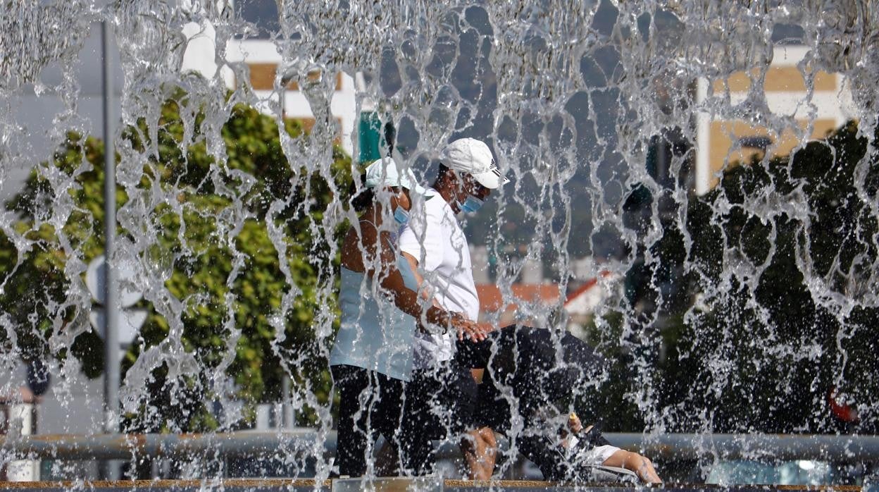 Dos personas tras los chorros de agua del Plan Renfe en un día de calor