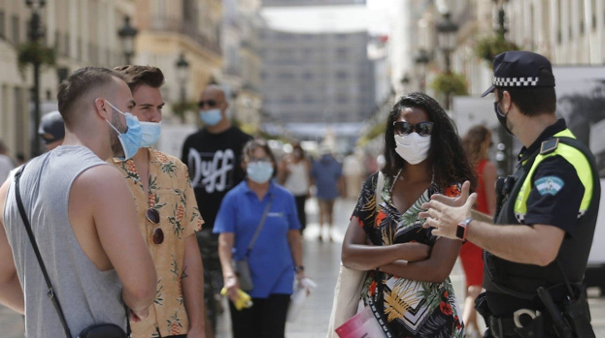 Un agente de la Policía Local conversa con varios viandantes en la calle Larios de Málaga