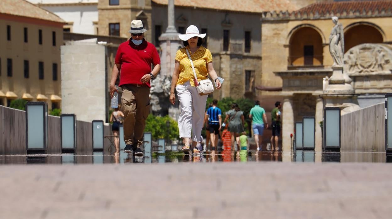 Dos personas cruzan el Puente Romano de Córdoba en plena tarde y con elevadas temperaturas