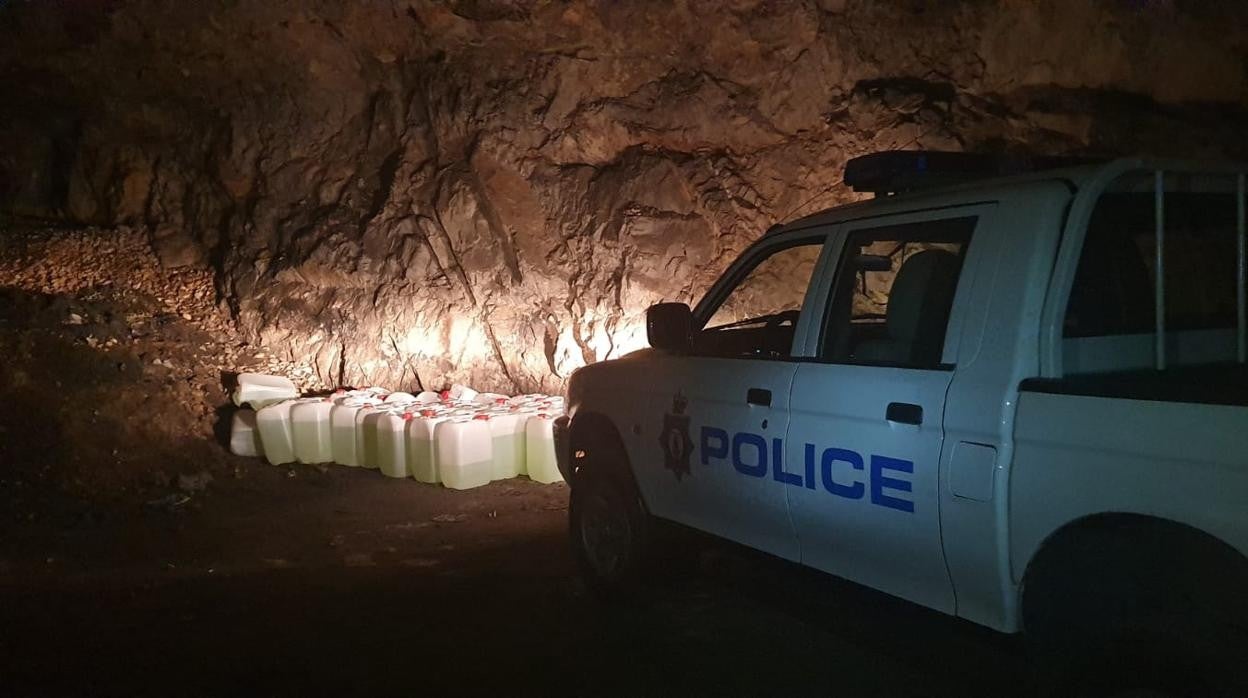 Imagen de un vehículo policial junto a algunas de las petacas encontradas en el túnel