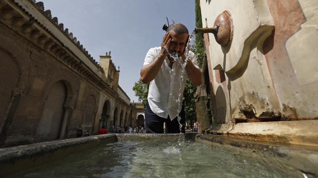 Un turista se refresca en una fuente este sábado en Córdoba en plena ola de calor