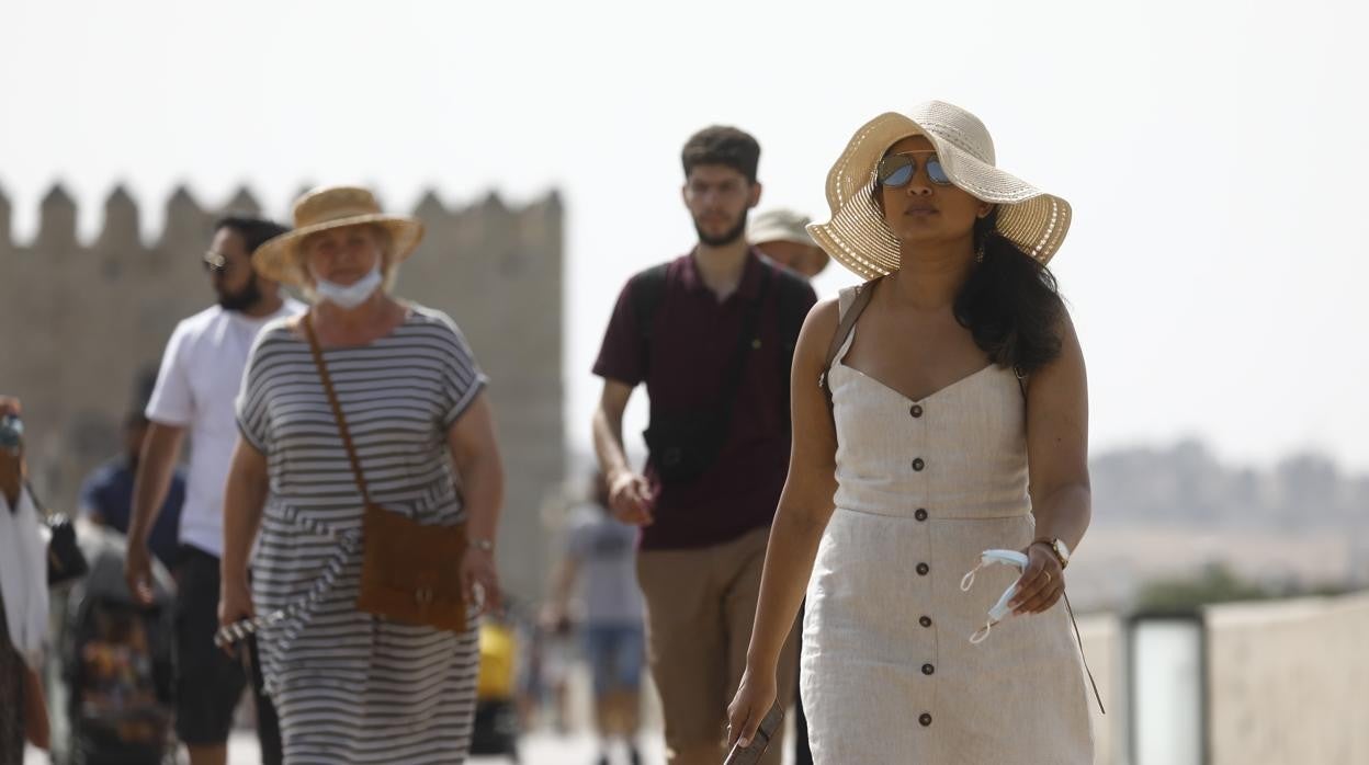 Los paseantes se protegen con sombreros del sol en el Puente Romano de Córdoba