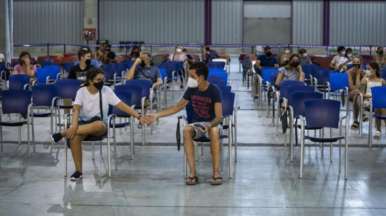 Jóvenes esperan tras recibir la vacuna en el Palacio de Ferias de Málaga