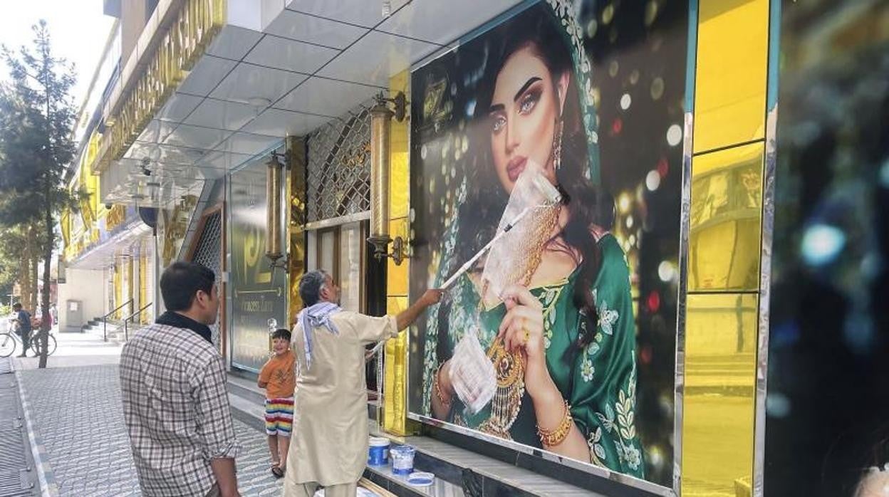 Un hombre tapa con pintura un cartel en un salón de belleza de Kabul el pasado 15 de agosto, ante la llegada de los talibán