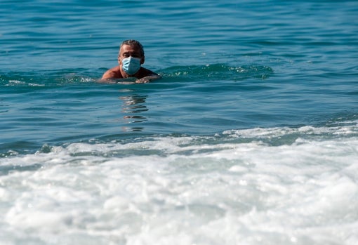 Un hombre se baña con mascarilla en una playa de Málaga