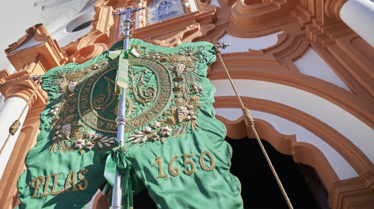 El simpecado de la Hermandad de Pilas ante las puertas de la Parroquia de la Asunción