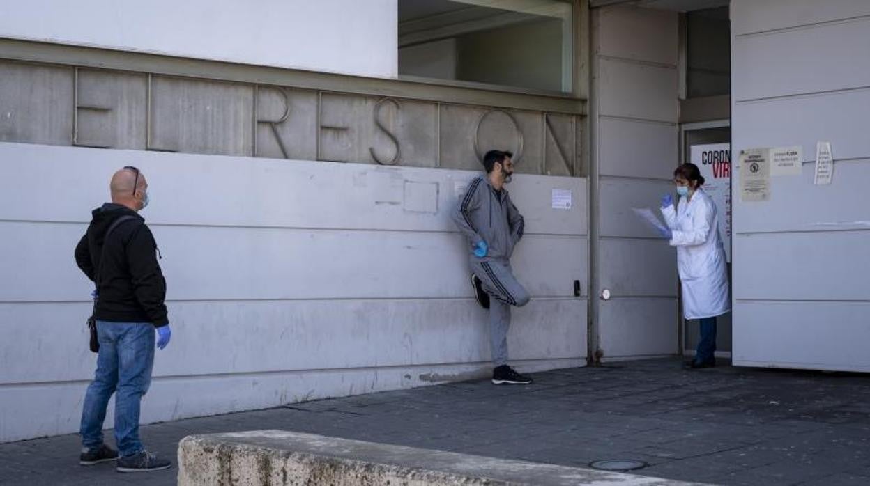 Una médico llama a un paciente que espera fuera del centro sanitario