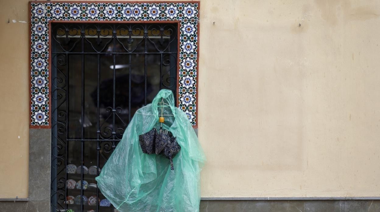 Un impermeable y un paraguas colgados de una reja