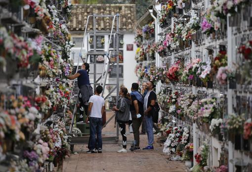 Una familia coloca flores en uno de los nichos del cementerio de San Rafael