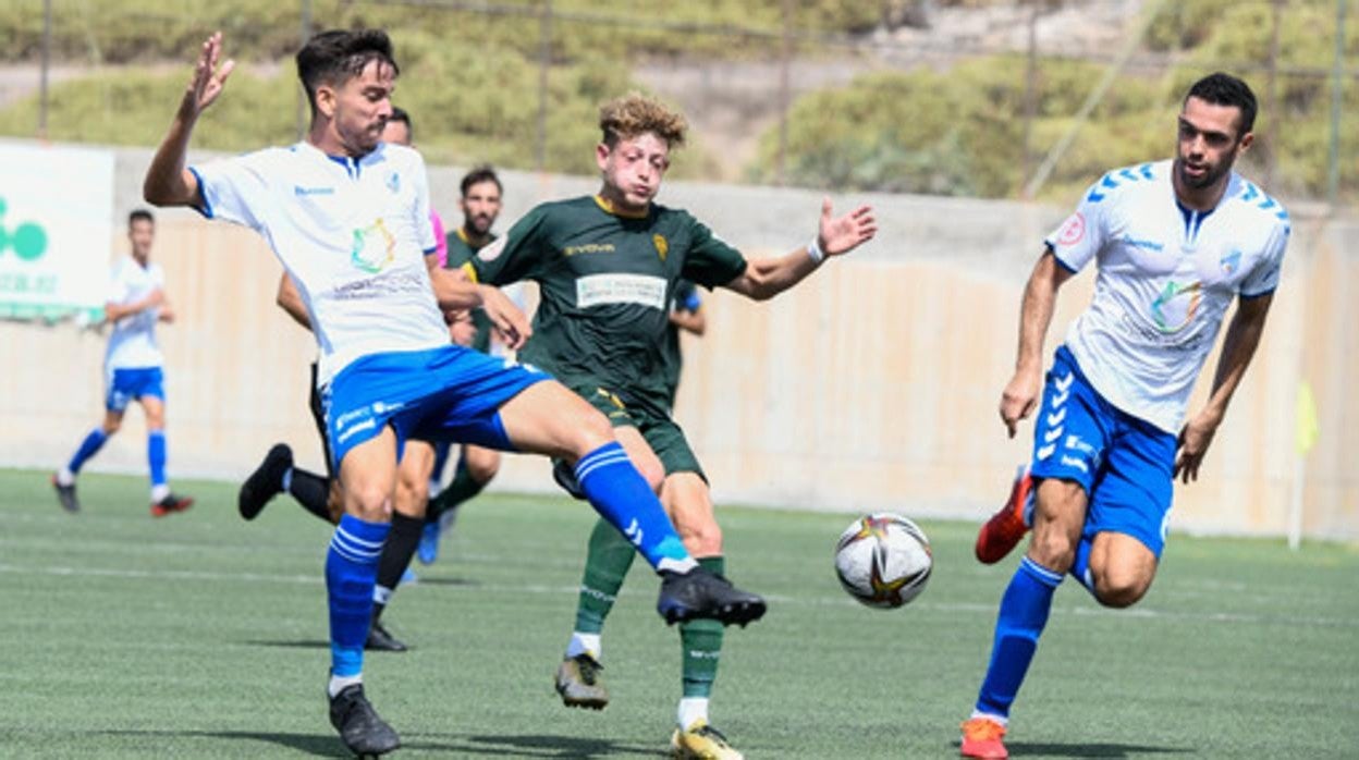 Simo busca robar un balón ante dos defensores del Tamaraceite