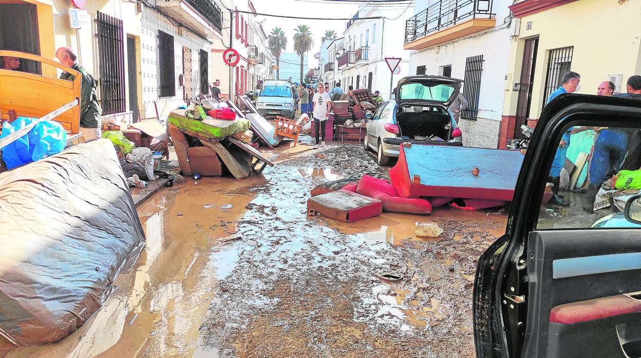 Vecinos de Lepe recogen enseres afectados por la lluvia en una de las calles de la localidad