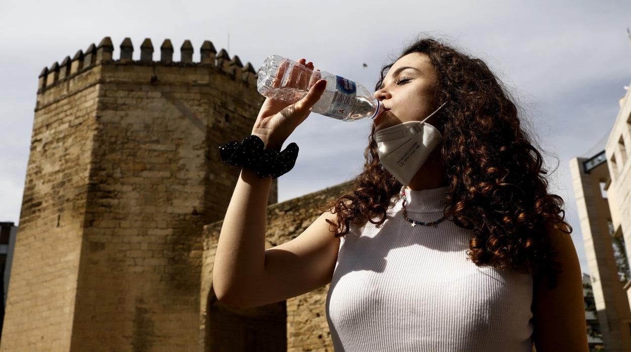 Una joven combate el calor bebiendo una botella de agua, junto a la Torre de la Malmuerta