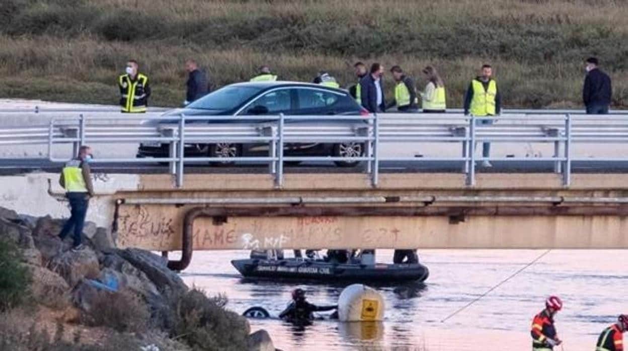 Bajo el puente, buzos de la Guardia Civil sacando el coche del agua