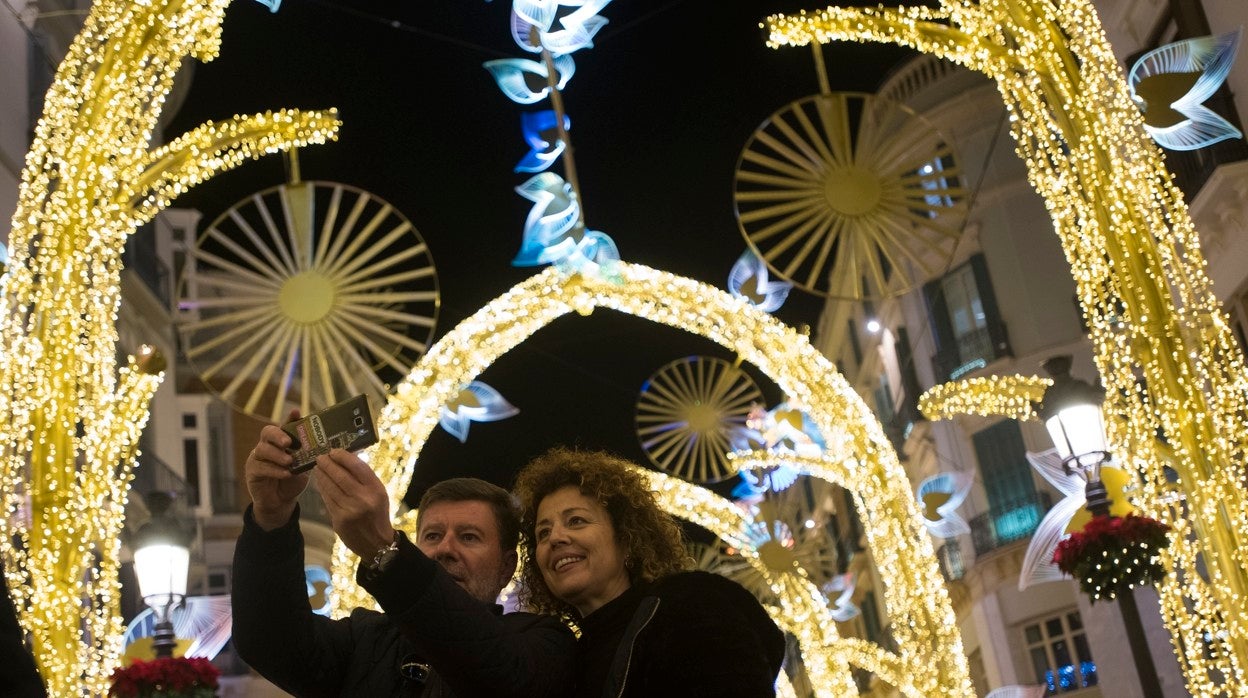 Una pareja se toma una foto bajo la bóveda de luces de la calle Larios