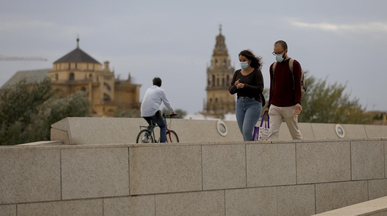 Dos paseantes y un ciclista en el puente de Miraflores