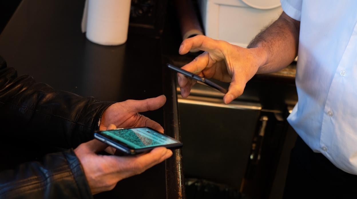 Un camarero escanea el código QR del certificado de vacunación de un cliente en un bar