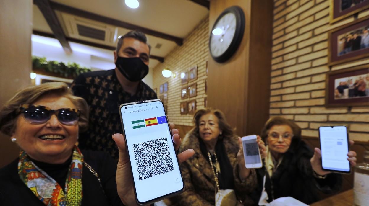 Varias mujeres muestran sus pasaportes Covid para entrar en un restaurante de Córdoba