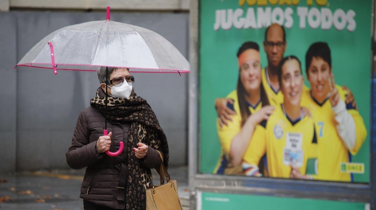 Una señora pasea con mascarilla por el Centro de Córdoba junto a un cartel publicitario