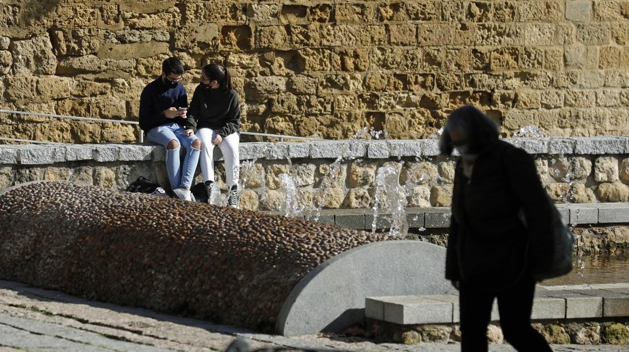 Una pareja cerca de la Puerta de Almodóvar mientras una mujer camina