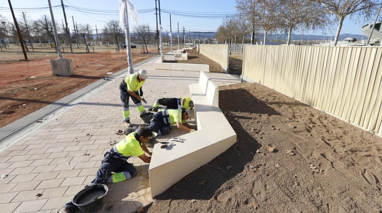 Varios operarios colocan ayer un banco en la nueva zona pavimentada de la calle Potro del recinto ferial