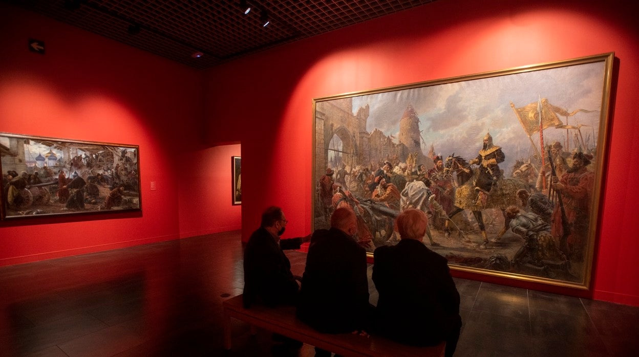 Tres hombres observan uno de los cuadros de la actual exposición 'Guerra y paz en el arte ruso'