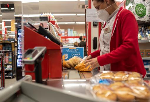 Una cajera pasando productos en un supermercado de Deza