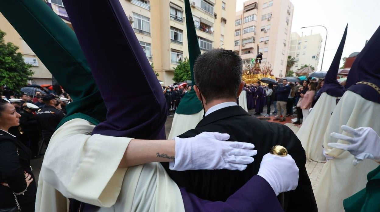 Nazarenos de Nueva Esperanza se abrazan al regresar a su casa hermandad por la lluvia intensa que ha caído a primera hora de la tarde