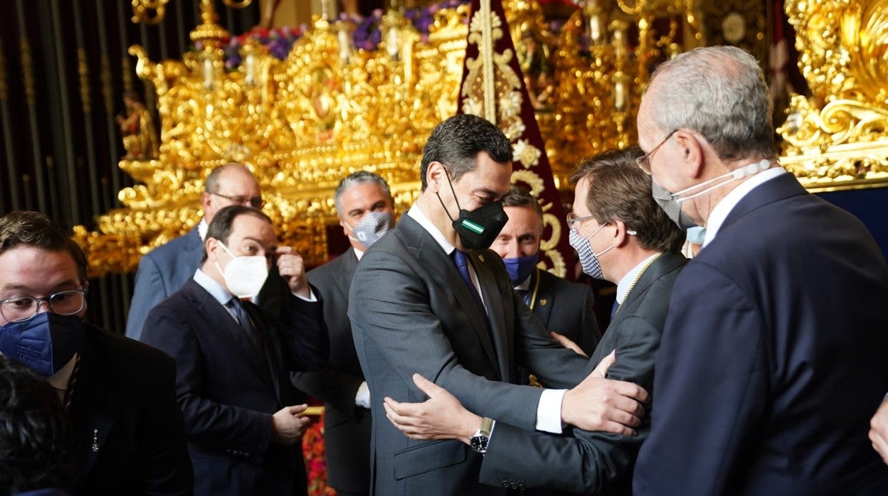 Juanma Moreno y José Luis Martínez-Almeida se saludan ante la mirada de Francisco de la Torre, alcalde de Málaga, junto al trono de La Paloma