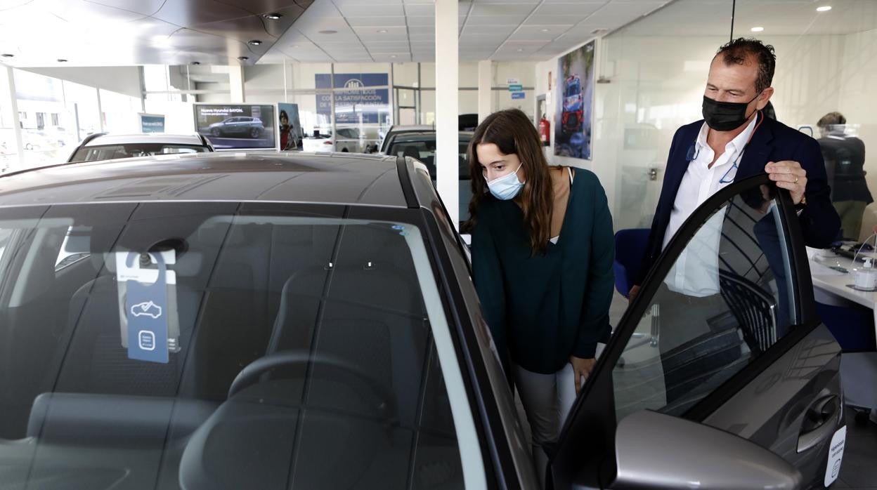 Una joven observa un turismo en un concesionario de coches en Córdoba