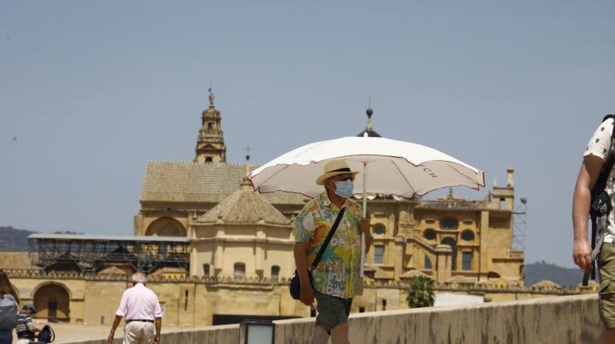 Un turista con sombrilla en el Puente Romano el pasado jueves