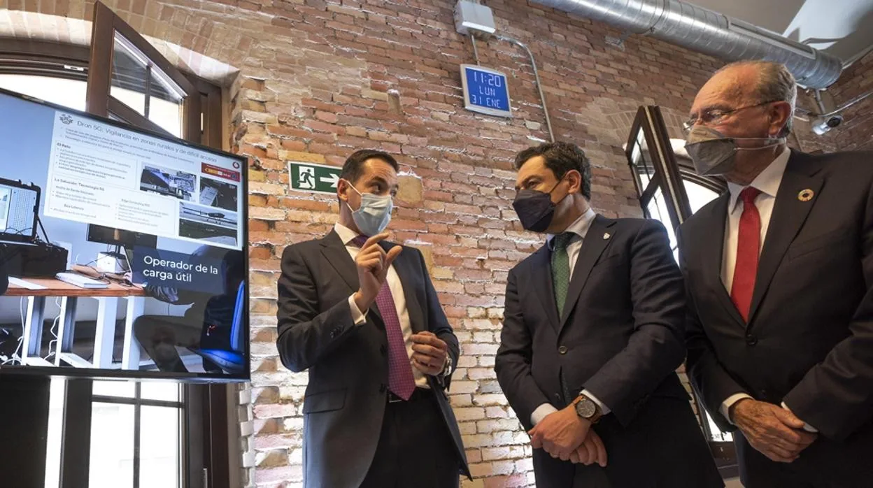 El presidente de la Junta de Andalucía, Juanma Moreno, y el alcalde de Málaga, Francisco de la Torre, atienden a uno de los directivos de la compañía durante la inauguración el pasado enero