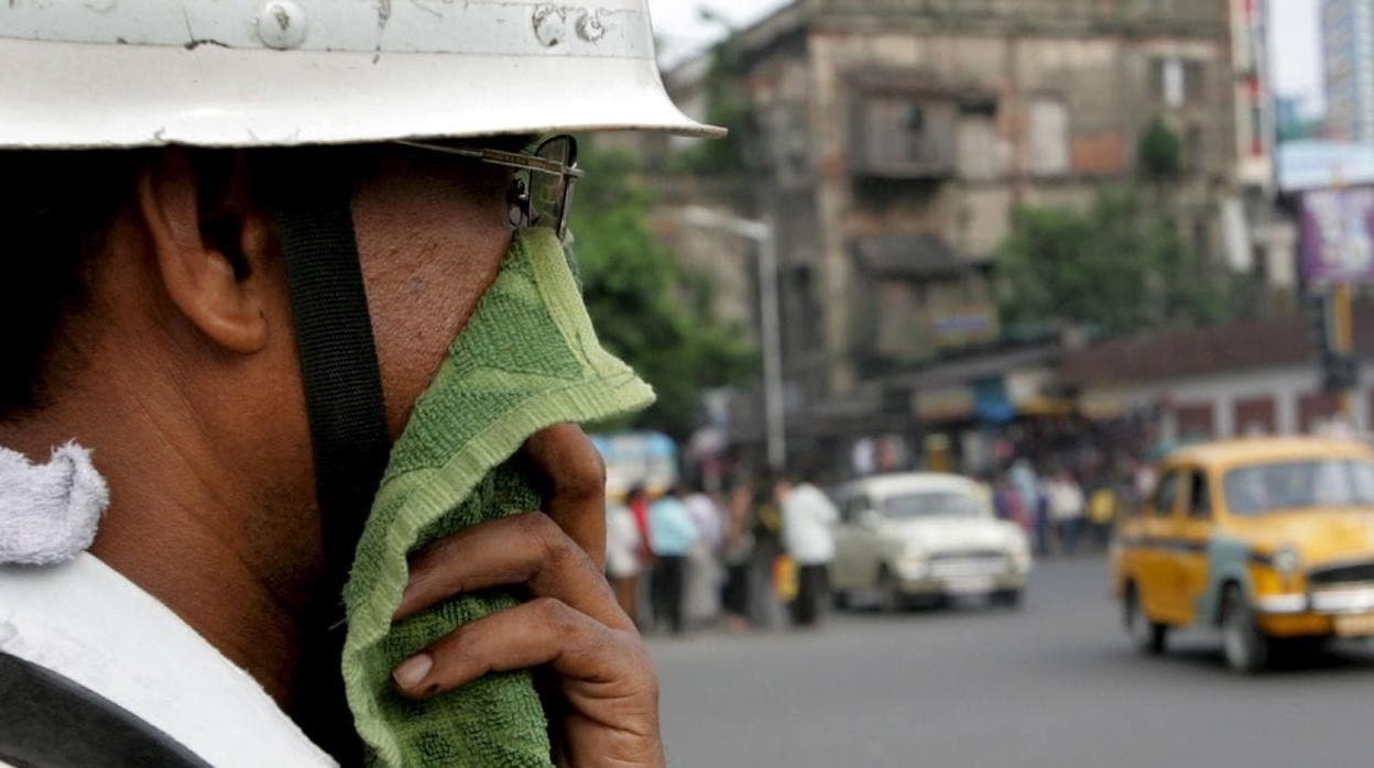 Un guardia de tráfico se protege de la polución en una avenida de Calcuta.