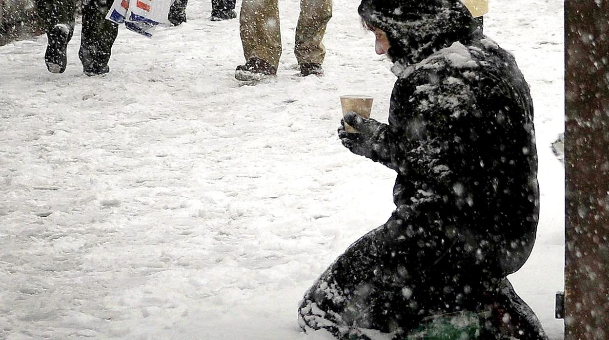 Una mujer pide en una calle nevada en Madrid.