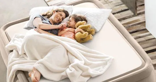 Una madre con su hija, en una cama de aire para interior.