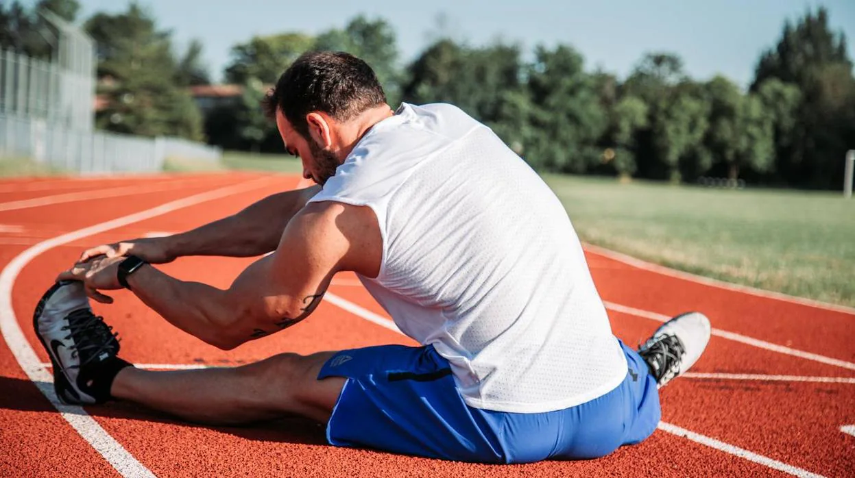 Un hombre estira en un pista de atletismo tras su sesión de entrenamiento