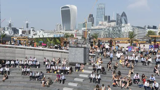 Los londinenses disfrutan del sol en la hora del almuerzo, en la City, ayer