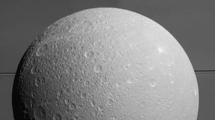 Dione con Saturno y sus anillos en el fondo