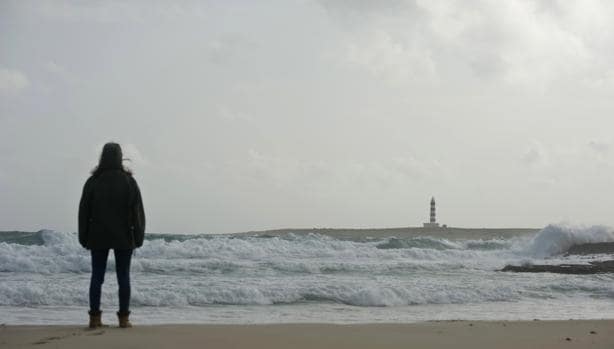 Un hombre contempla el mar desde la playa de Punta Prima, en el municipio de San Lluís, afectada por el temporal de lluvia y viento.