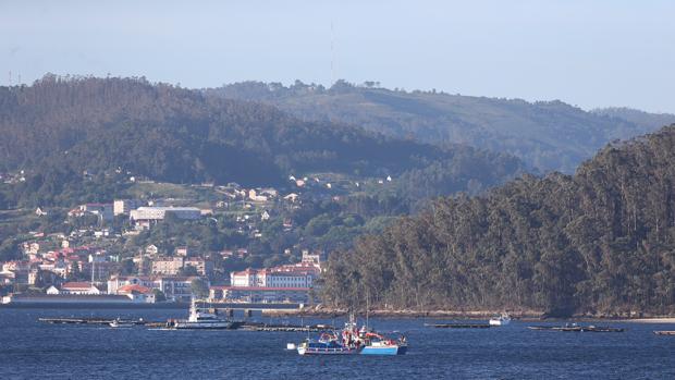 Una embarcación de Salvamento Marítimo, junto a la batea donde chocó el pesquero en la ría de Pontevedra