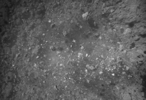 Imagen de la superficie del asteroide Ryugu justo después del aterrizaje. Los escombros salen disparados hacia arriba
