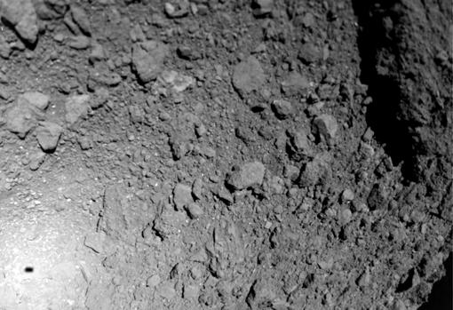 Imagen de la superficie de Ryugu durante el descenso de MASCOT. A la izquierda se ve la sombra del robot, de 30 cm de largo, y a la derecha, arriba, un bloque de decenas de metros de largo