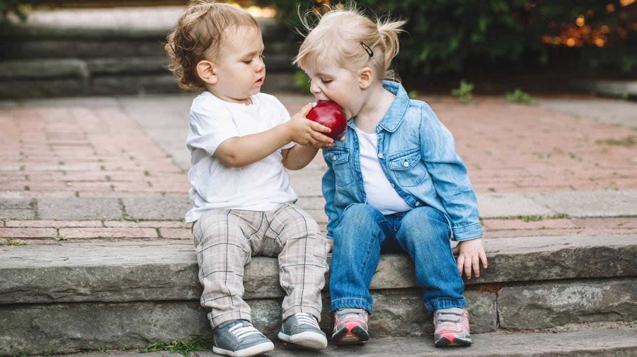 Dos niños pequeños comparten una manzana