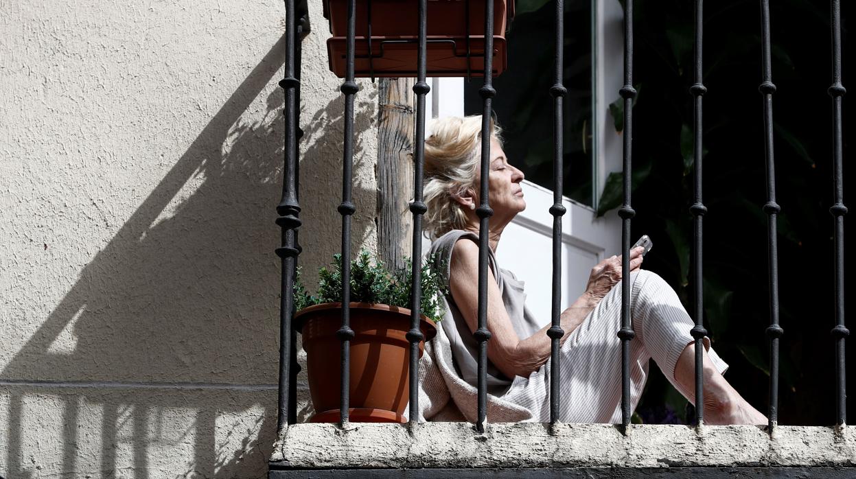 Una mujer toma el sol en su casa de Madrid durante el confinamiento