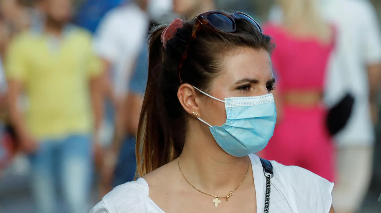 Una mujer camina por Nápoles, ciudad en la que el uso de la mascarilla es obligatorio en zonas cercanas a bares, pubs y concentraciones de personas