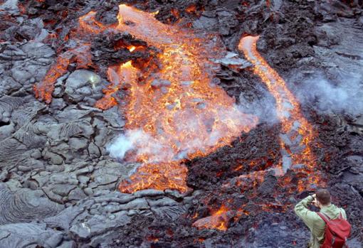 Un hombre toma una fotografía mientras la lava fluye desde el Fagradalsfjall