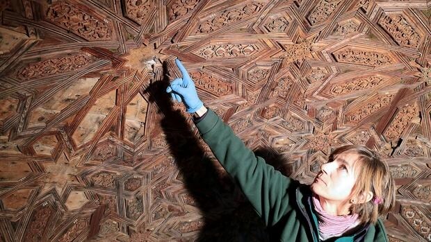Una restauradora señala las piezas de madera que conforma la cúpula del templete oeste del Patio de los Leones