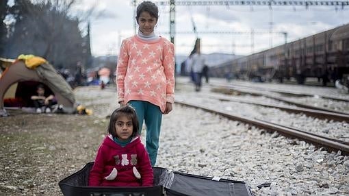 Unas niñas sirias juegan con una maleta en la estación de tren de Idomeni (Grecia)